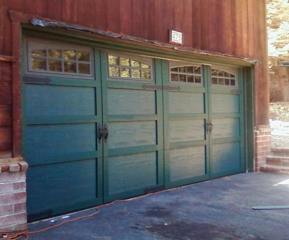 A green carriage-style garage door with windows and decorative hardware installed by Overhead Door of Sierra Nevada in Reno, NV.