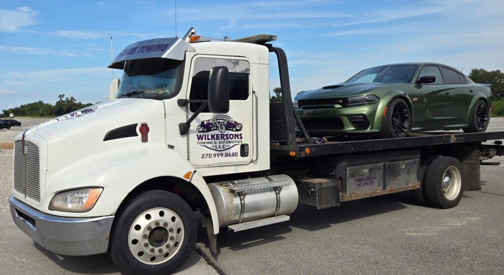 A green Dodge Charger Hellcat sedan loaded onto a flatbed tow truck from Wilkerson's Towing & Automotive LLC in Bowling Green, KY.