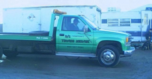 A green flatbed tow truck with 'TOWING SERVICE' written on its side, representing D & S Towing in San Tan Valley, AZ.