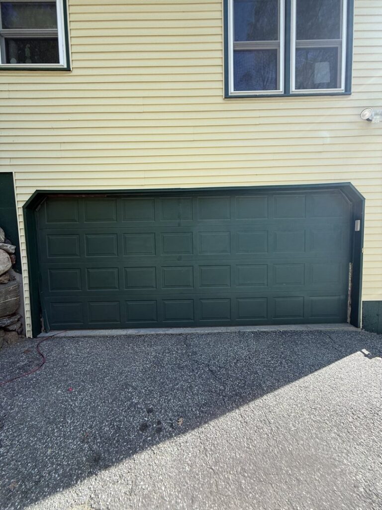 A green garage door installed on a yellow house by Mascolo Overhead Doors & Maintenance in Brookfield, CT.