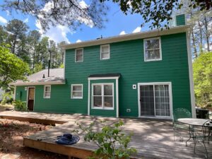 The back of a house with vibrant green horizontal siding and a wooden deck by Ideal Siding Winston-Salem, NC.