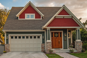 A green house featuring a light-colored garage door with windows by Jim Dyer Overhead Door in Carson City, NV