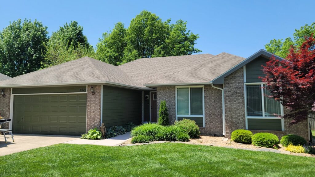 A residential project showcasing new green horizontal siding and brick accents by Xtreme Exteriors in Rogers, AR.