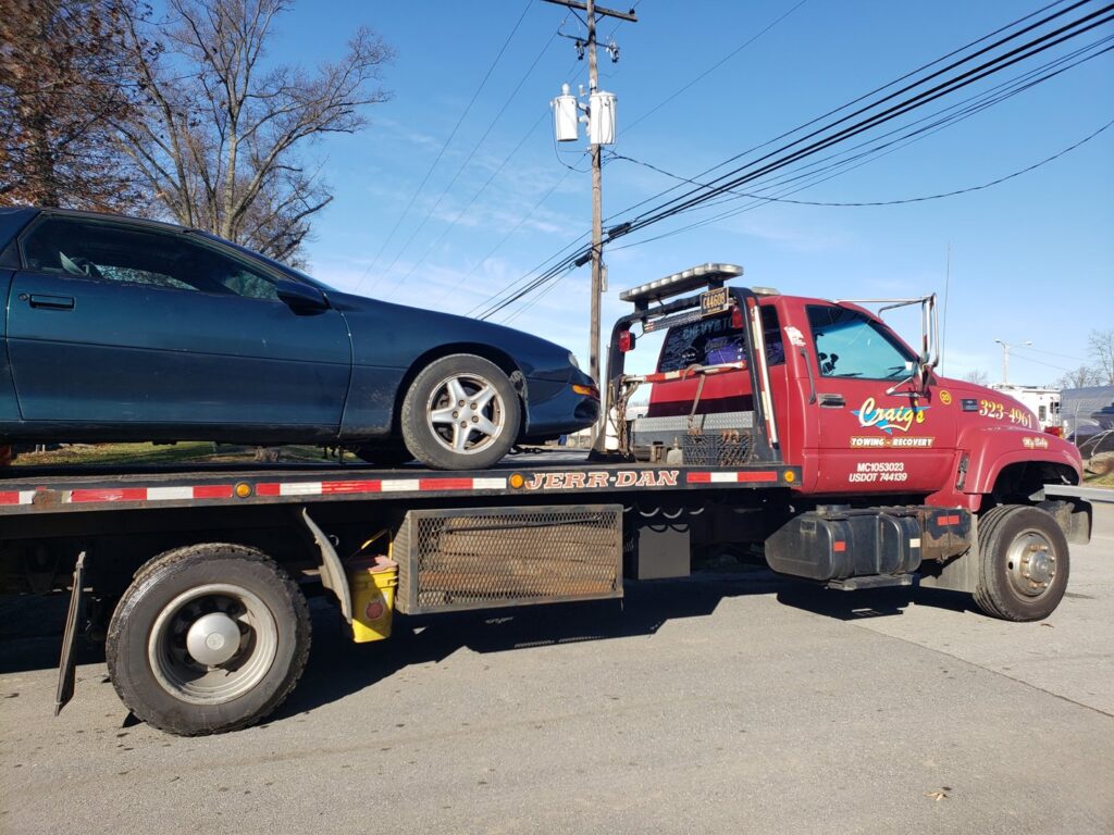 A green sports car fully loaded on a flatbed tow truck from Craig's Towing & Recovery in New Castle, DE.