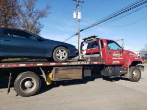 A green sports car fully loaded on a flatbed tow truck from Craig's Towing & Recovery in New Castle, DE.