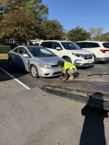 A green SUV being towed on a flatbed tow truck at night by Hampton Roads Towing Services in Chesapeake, VA.