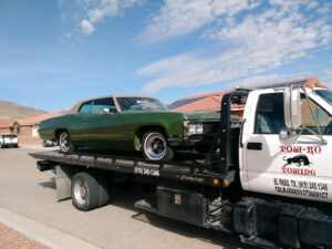 A green vintage convertible car being transported on a flatbed tow truck by Tow-Ro Towing in El Paso, TX.