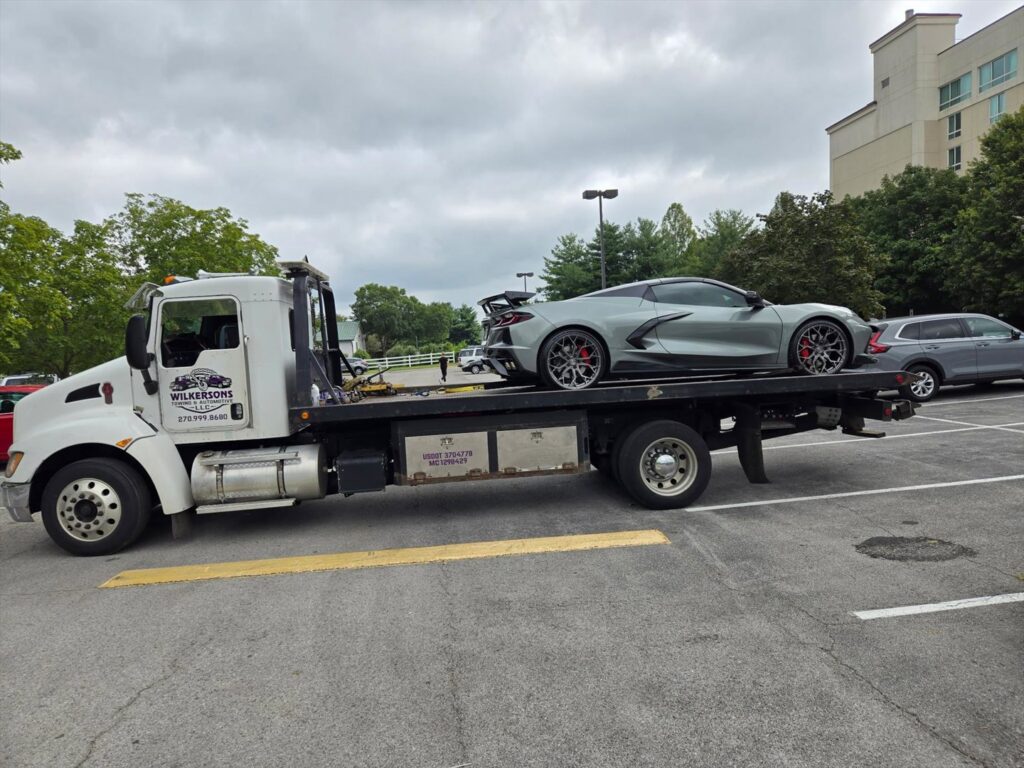 A grey Corvette sports car loaded onto a flatbed tow truck from Wilkerson's Towing & Automotive LLC in Bowling Green, KY.