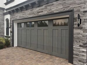 Grey garage door with top windows installed on a stone house by Garage Doors & More in Bentonville, AR