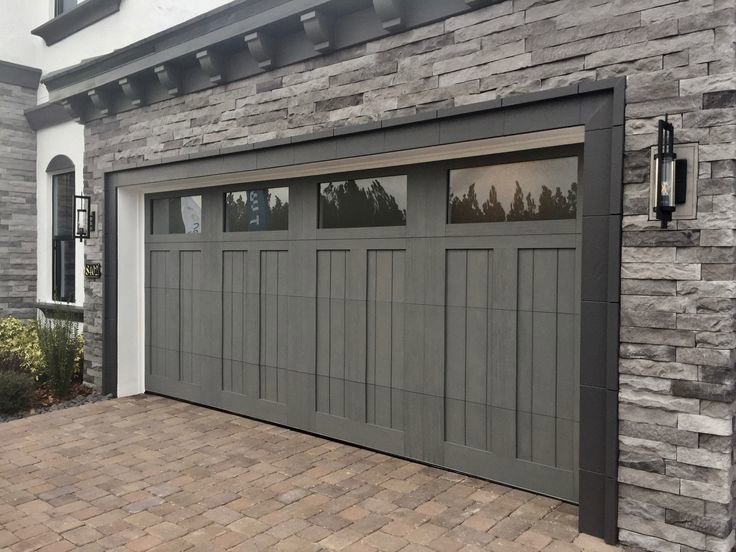 Grey garage door with top windows installed on a stone house by Garage Doors & More in Bentonville, AR