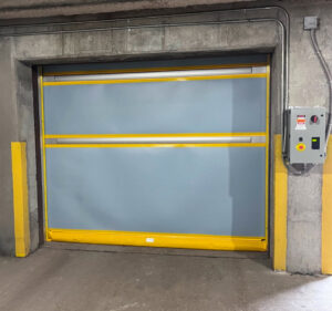 A grey high-speed roll-up door with yellow safety accents, installed by Canyon Overhead Doors in Salt Lake City, UT.