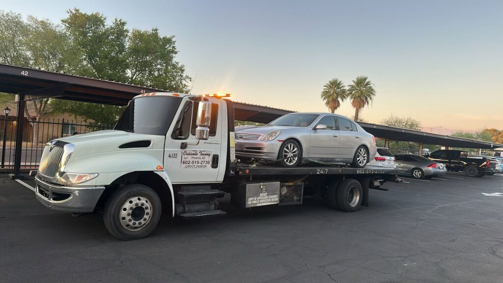 A grey Jeep Wrangler being transported on a flatbed tow truck by Crisanto Towing in Phoenix, AZ.