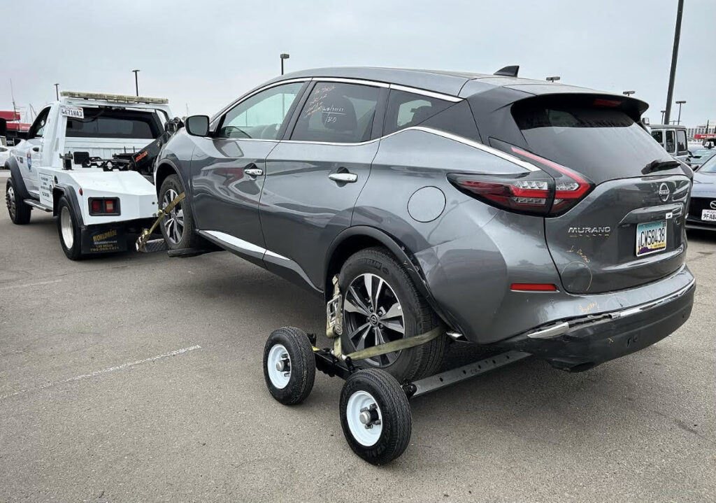 A grey Nissan Murano SUV being towed with a wheel lift and dollies by Cali kings Towing in San Diego, CA.