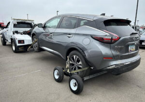 A grey Nissan Murano SUV being towed with a wheel lift and dollies by Cali kings Towing in San Diego, CA.