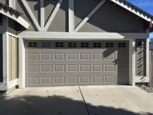 A newly installed grey paneled garage door with decorative windows by Summit-Overhead-Door in Sparks, NV.