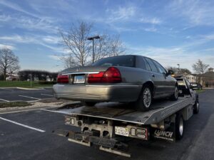 A grey sedan being transported on a flatbed tow truck by Towing Recovery Rebuilding Assistance Services in Naperville, IL