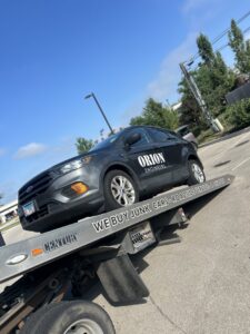 A grey SUV being transported on a flatbed tow truck by Towing Recovery Rebuilding Assistance Services in Naperville, IL