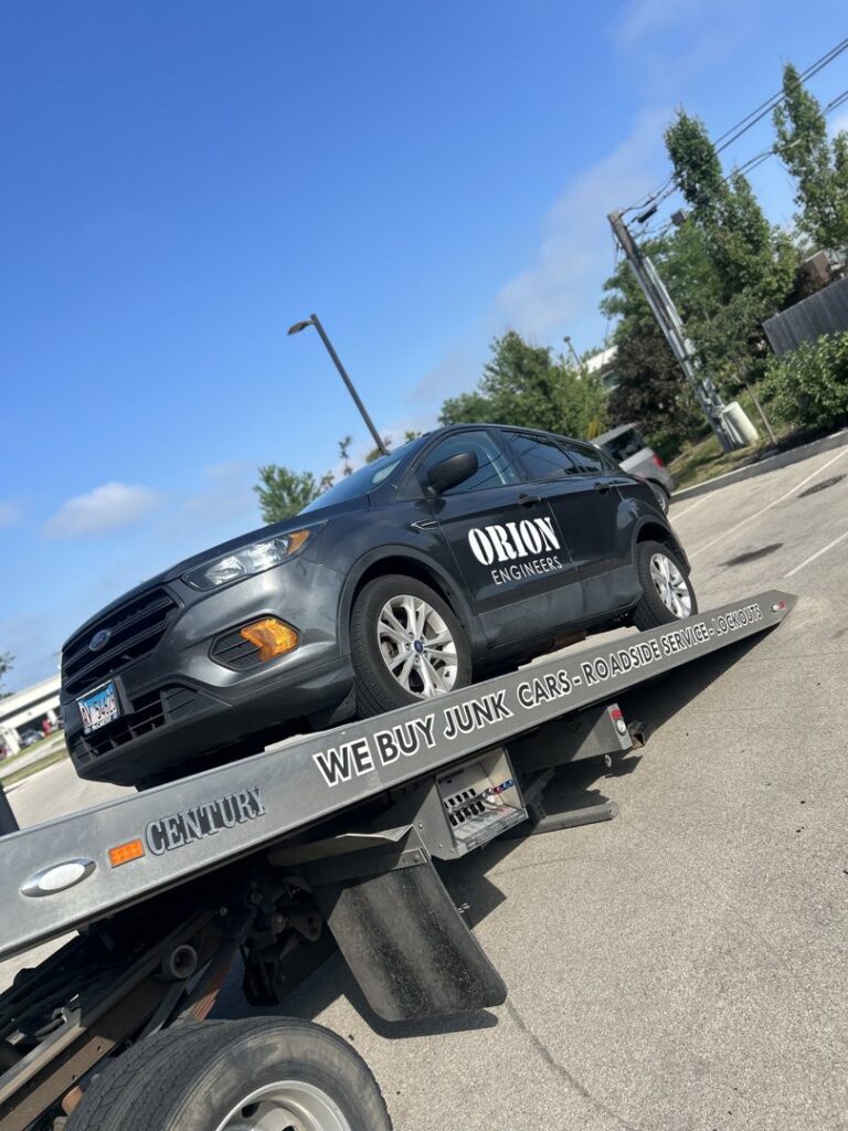 A grey SUV being transported on a flatbed tow truck by Towing Recovery Rebuilding Assistance Services in Naperville, IL
