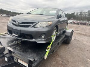 A grey Toyota Corolla secured on a car trailer for transport by Grace to Grace Towing in Atlanta, GA.