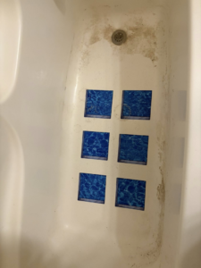 A grimy bathtub with visible dirt and stains before cleaning by Warm & Cozy House Cleaning in Madison, WI