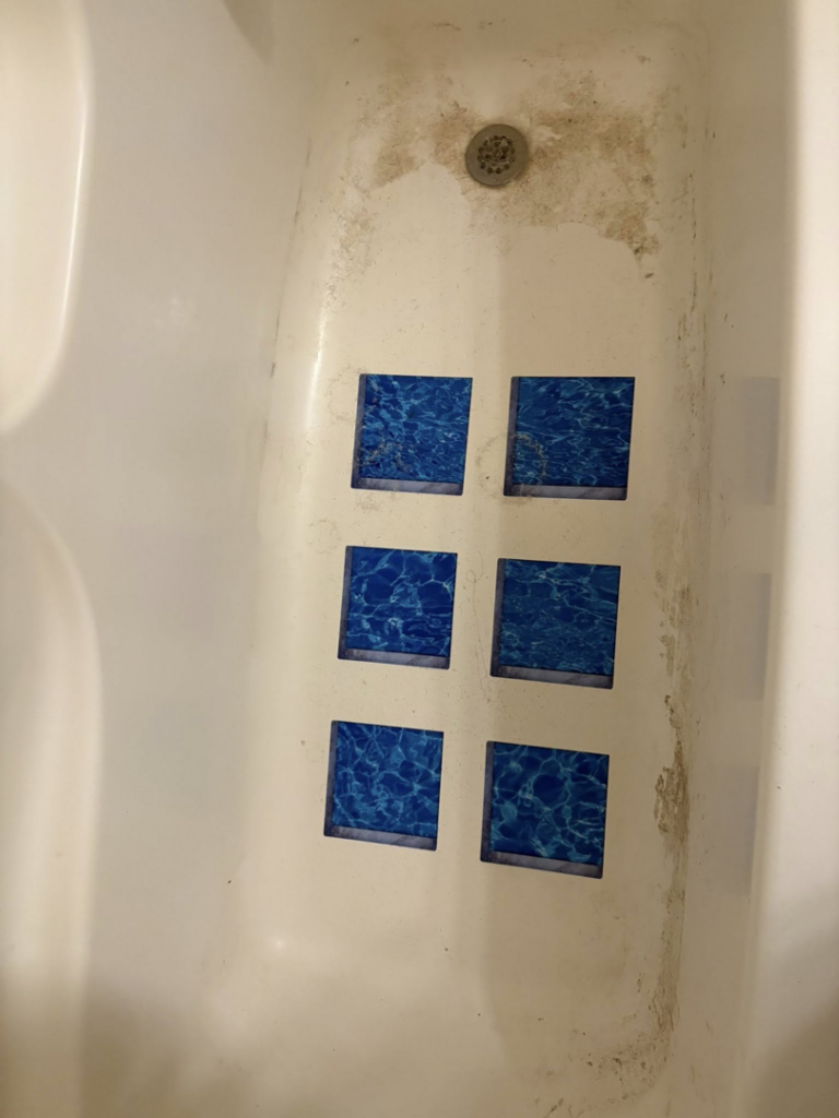 A grimy bathtub with visible dirt and stains before cleaning by Warm & Cozy House Cleaning in Madison, WI