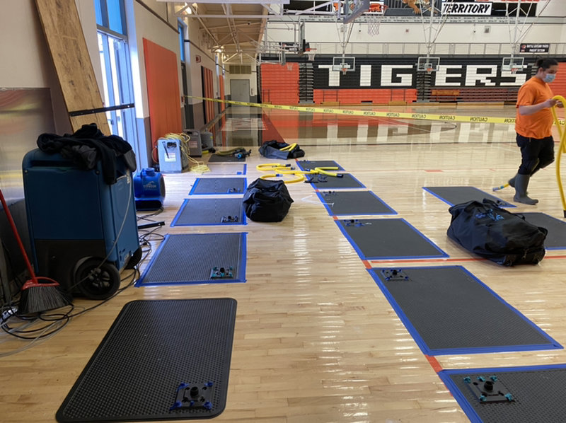 A gym floor being dried with specialized mats and dehumidifiers by Paul Davis Restoration of Portland / Vancouver in Vancouver, WA