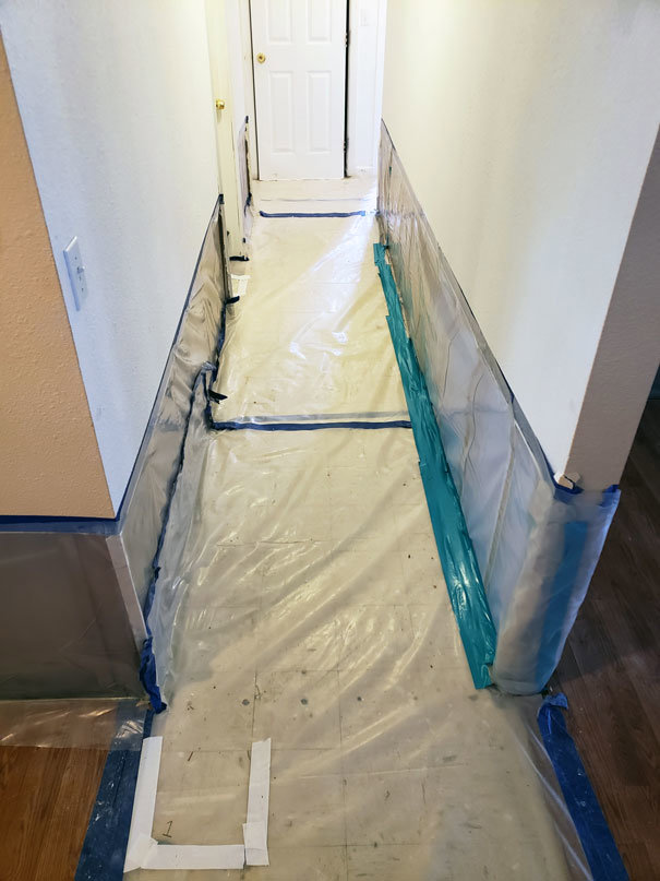 A hallway protected with plastic sheeting and tape, indicating a water damage containment zone by Island Restoration LLC in Kapolei, HI.