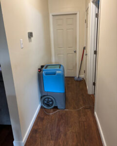 Blue dehumidifier operating in a hallway for water damage drying by 1st Response Emergency Repairs, LLC in Scott, LA.