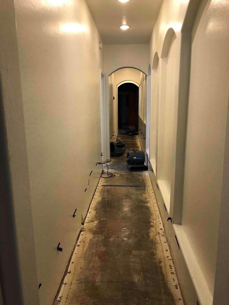 A hallway with air movers and drying equipment set up for water damage restoration by Lotus Restoration Services in Gilbert, AZ.