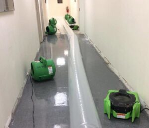 A hallway undergoing water damage restoration with a drying tube and air movers from SERVPRO of Newark in Wilmington, DE
