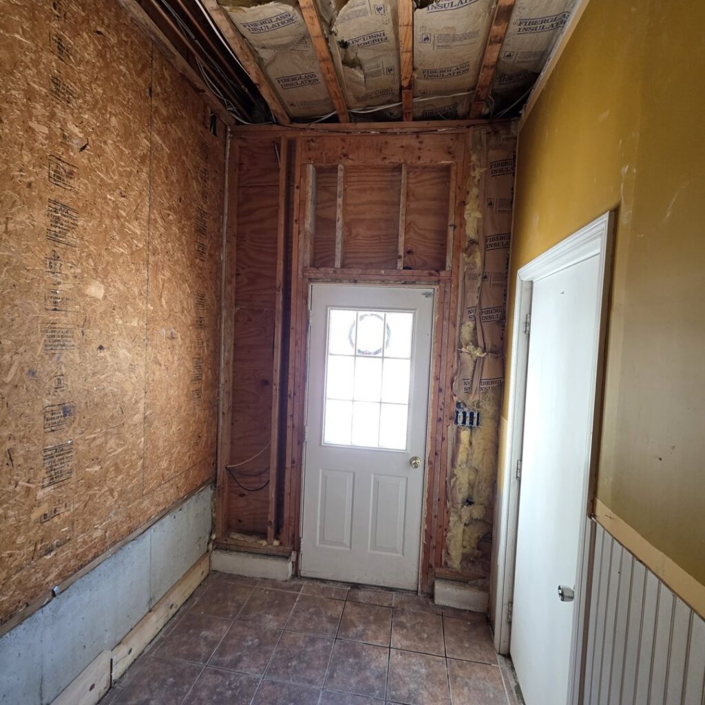 A hallway with walls stripped to studs, showing remediation work by PuroClean of Strafford County in Nottingham, NH.