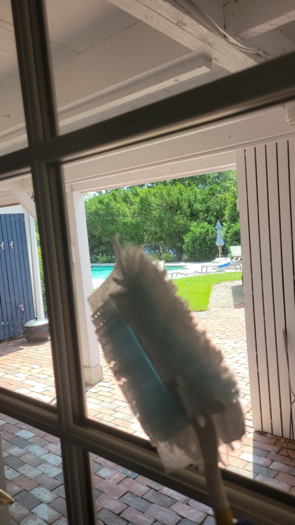 A professional house cleaner dusting a window at a client's home by Solange D Kleaner in New Bedford, MA.