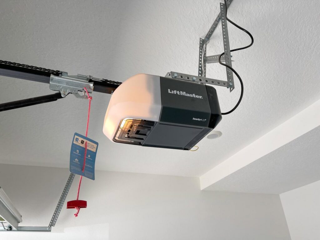 A hand pulling the emergency release cord of a garage door opener, a common action during service by DNA Garage Door Repair in New Haven, CT