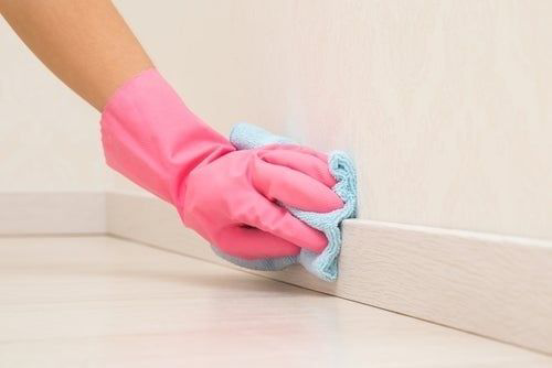 A gloved hand meticulously wiping a baseboard, demonstrating attention to detail by Total Refresh Housekeeping in Springfield, OR