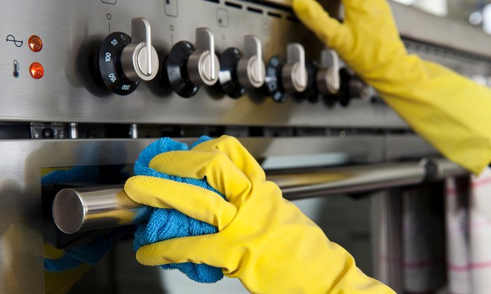 A hand wiping a wooden surface with a blue microfiber cloth, showcasing the cleaning services of Your Green Clean Crew in Bellevue, WA.