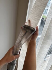 Hands using a specialized tool to clean vertical blinds, a service offered by FM Cleaning in West Fargo, ND.