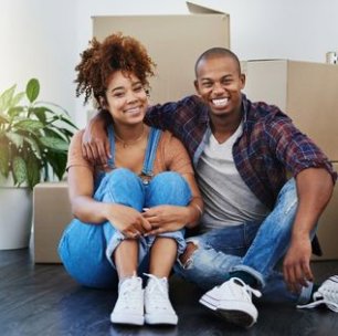 A happy couple sitting on the floor surrounded by moving boxes, ready for their QuickTotes move in Indianapolis, IN.
