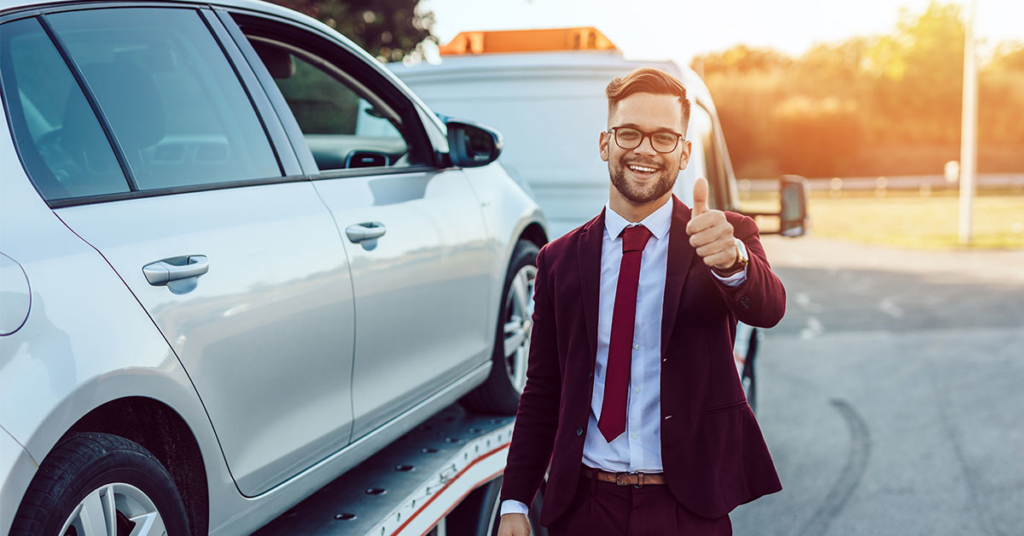 A happy customer giving a thumbs up as their car is loaded onto a tow truck by Atlantis Towing Services in Chicago, IL.