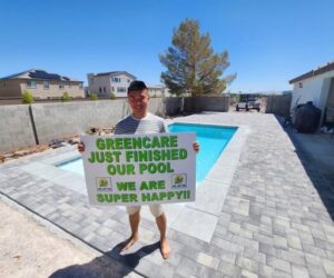 A happy customer holding a sign about their newly finished pool by Greencare.net POOL Builder in Las Vegas, NV