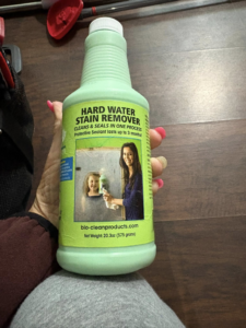 A hand holding a bottle of Hard Water Stain Remover used by Danielle's cleaning service in Xenia, OH