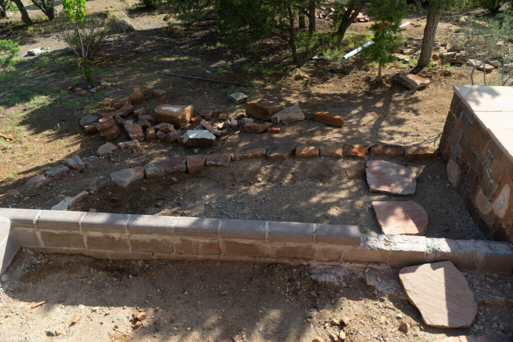 A hardscaping project in progress featuring a low brick wall and stone slabs by Pro Scape in Eustis, FL.