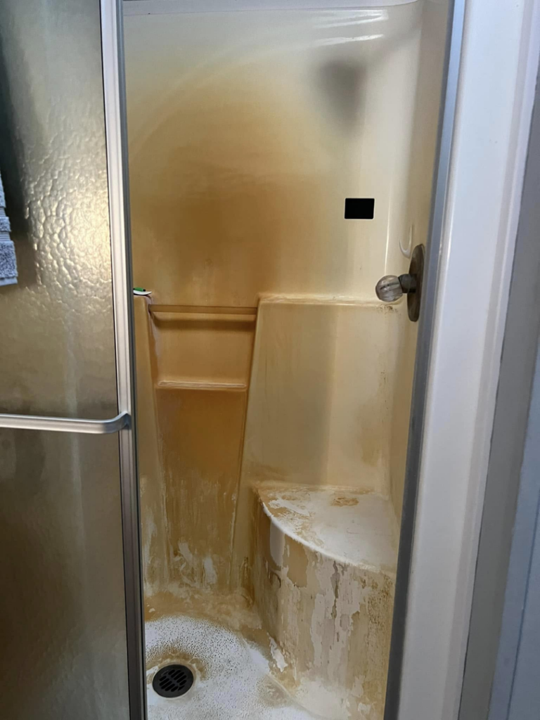 A heavily soiled shower stall with significant buildup before cleaning by Crystal's Small Town Cleaning Company, LLC in Oelwein, IA.