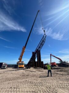 A heavy crane truck from CC Wrecker Service lifting a large metal structure at a site in Corpus Christi, TX.