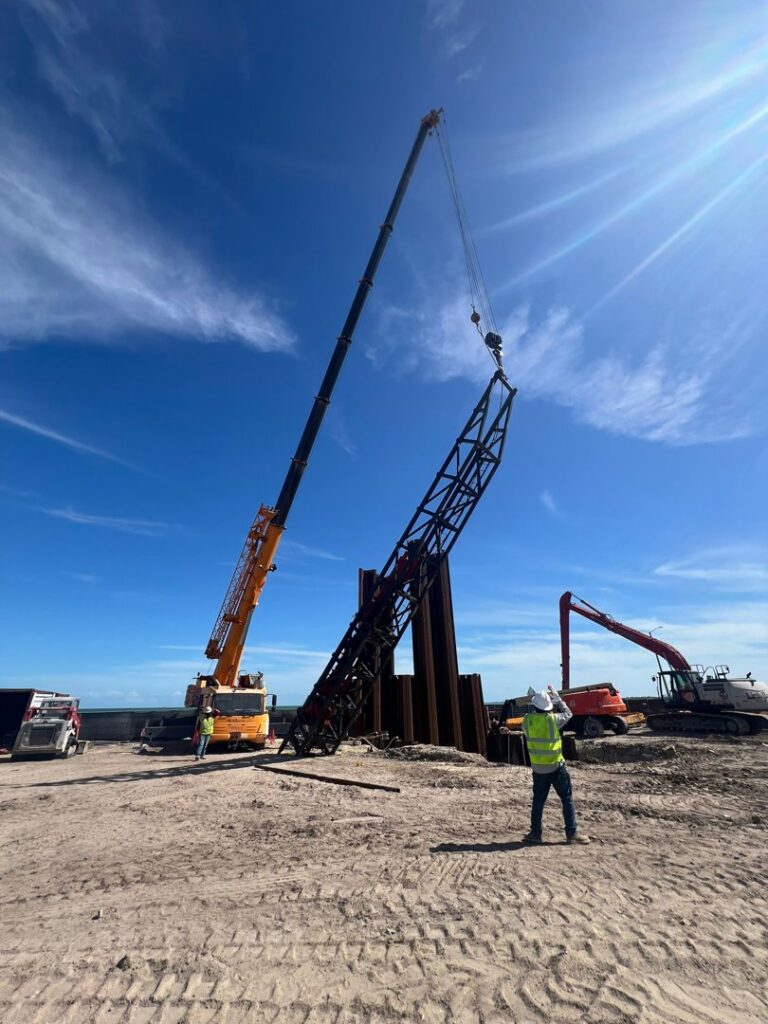 A heavy crane truck from CC Wrecker Service lifting a large metal structure at a site in Corpus Christi, TX.