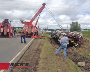 Two heavy-duty tow trucks from Rick's Towing and Recovery in Lafayette, LA, recovering an overturned tanker truck.