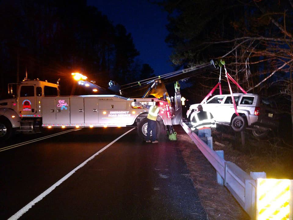A heavy-duty wrecker recovering a white SUV from a ditch at night for Southern Maryland Towing in Prince Frederick, MD.