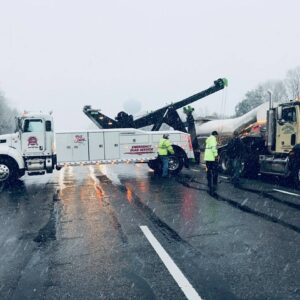 A heavy-duty wrecker assisting a tanker truck on a snowy road for Southern Maryland Towing in Prince Frederick, MD.