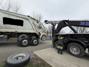 A heavy-duty tow truck from Bevis Towing lifting a large garbage truck during a recovery job in Cincinnati, OH.