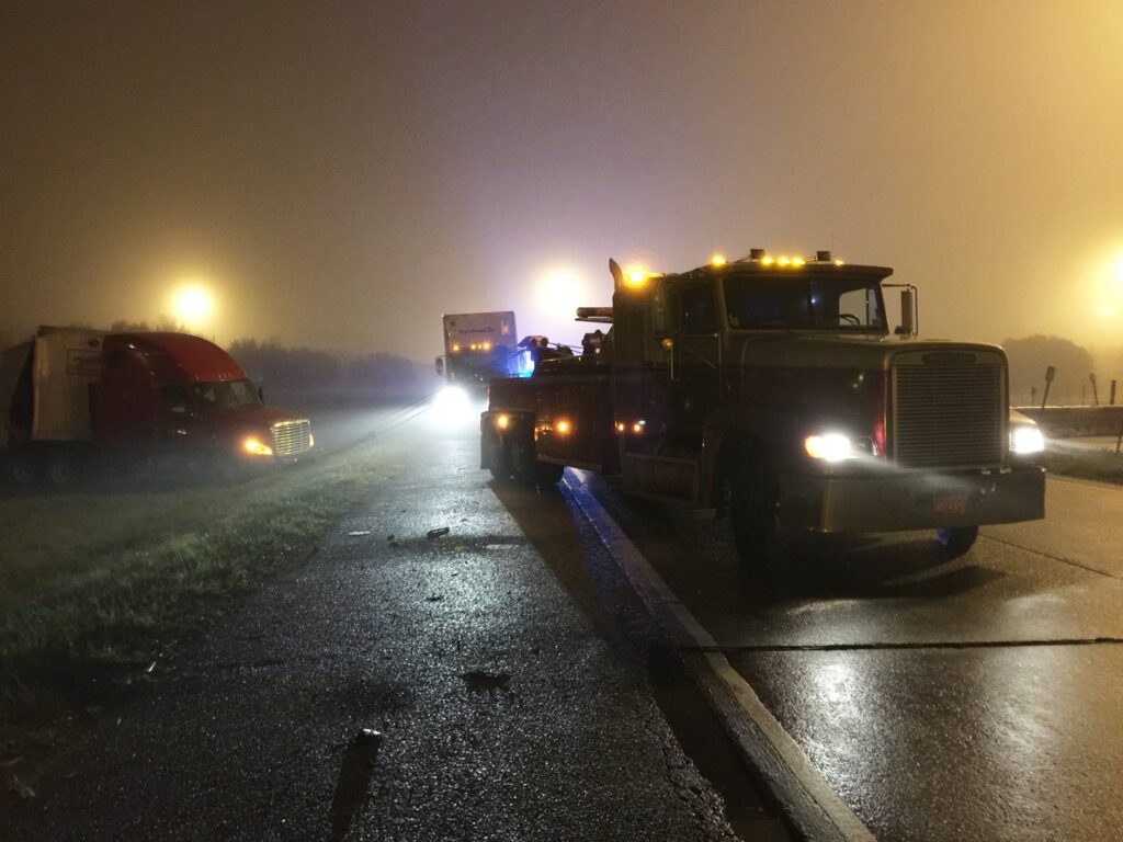 A heavy-duty tow truck from Glenn's Towing & Recovery Inc assisting a semi-truck on a highway at night in Lafayette, LA.