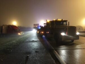 A heavy-duty tow truck from Glenn's Towing & Recovery Inc assisting a semi-truck on a highway at night in Lafayette, LA.